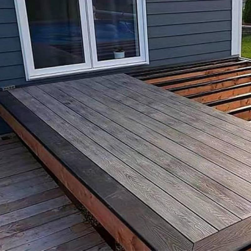 A shipping container being loaded with neatly stacked composite decking boards.